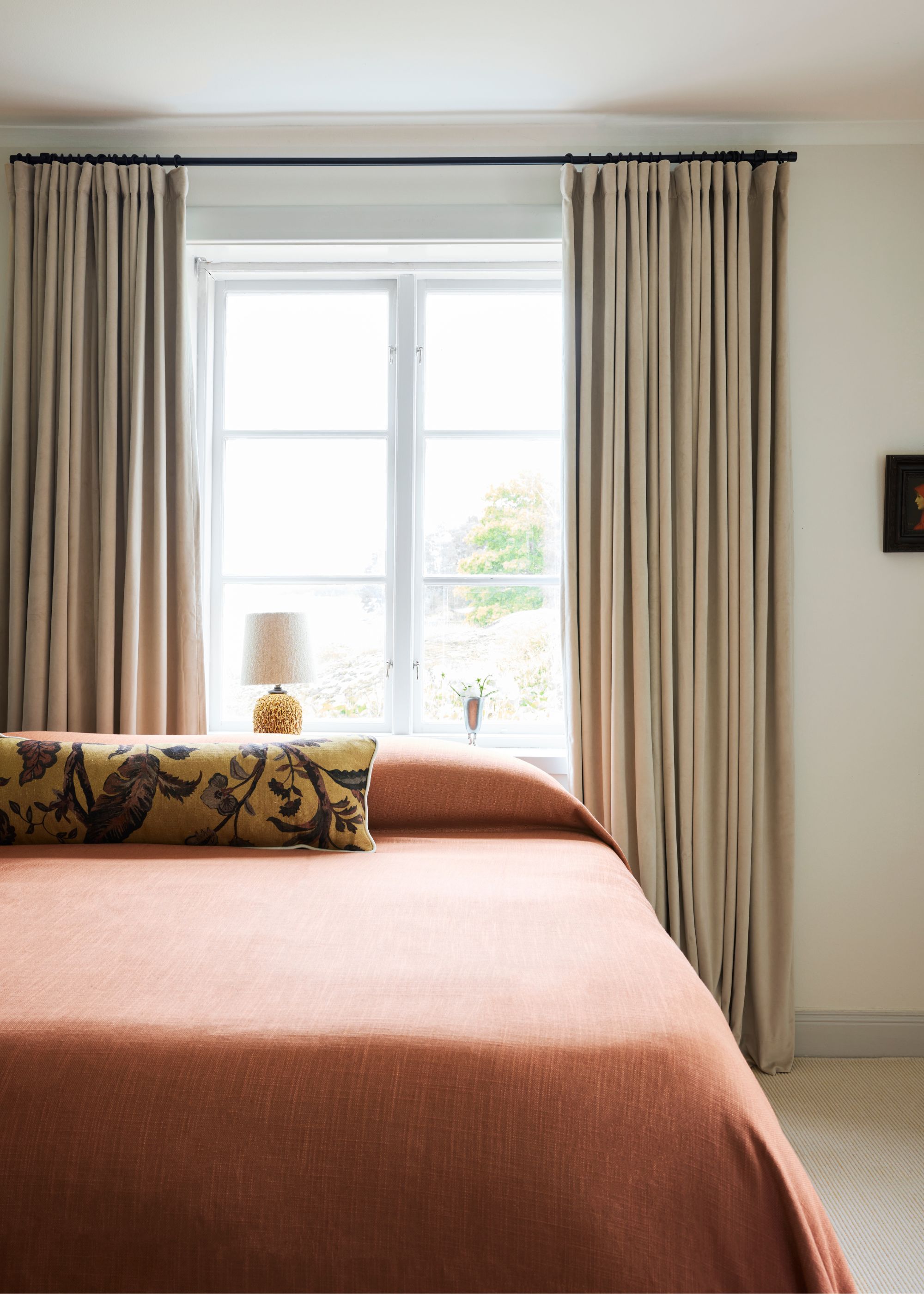 modern bedroom with rust colored bedding and neutral velvet curtains
