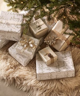 Christmas gifts wrapped in white and champagne wrapping topped with sparkling decorations