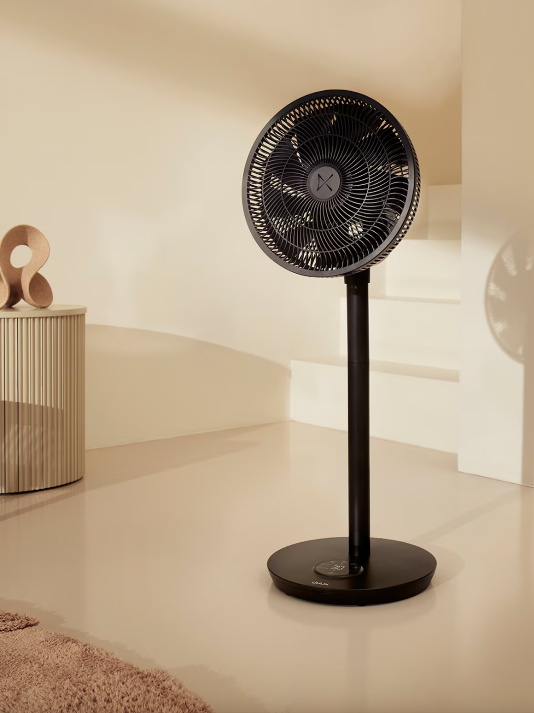 A standing black pedestal fan from Duux in a living room