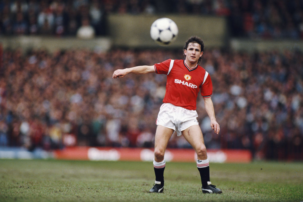 Le défenseur de Manchester United, Arthur Albiston, passe un ballon de football adidas tango lors d'un match de League Division One contre Manchester City à Old Trafford en mars 1986 à Manchester, en Angleterre.