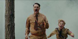 Taika Waititi as Hitler running with Roman Griffin Davis as Jojo in Jojo Rabbit