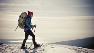 A woman snowshoeing across flat terrain with a big backpack