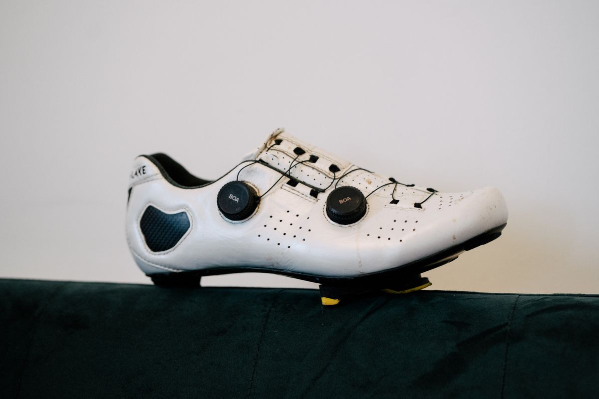 A white leather cycling shoe on a green sofa