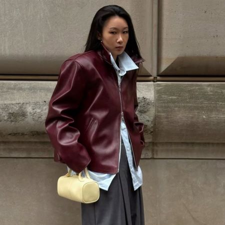 A woman wears a light yellow handbag with a dark red jacket.