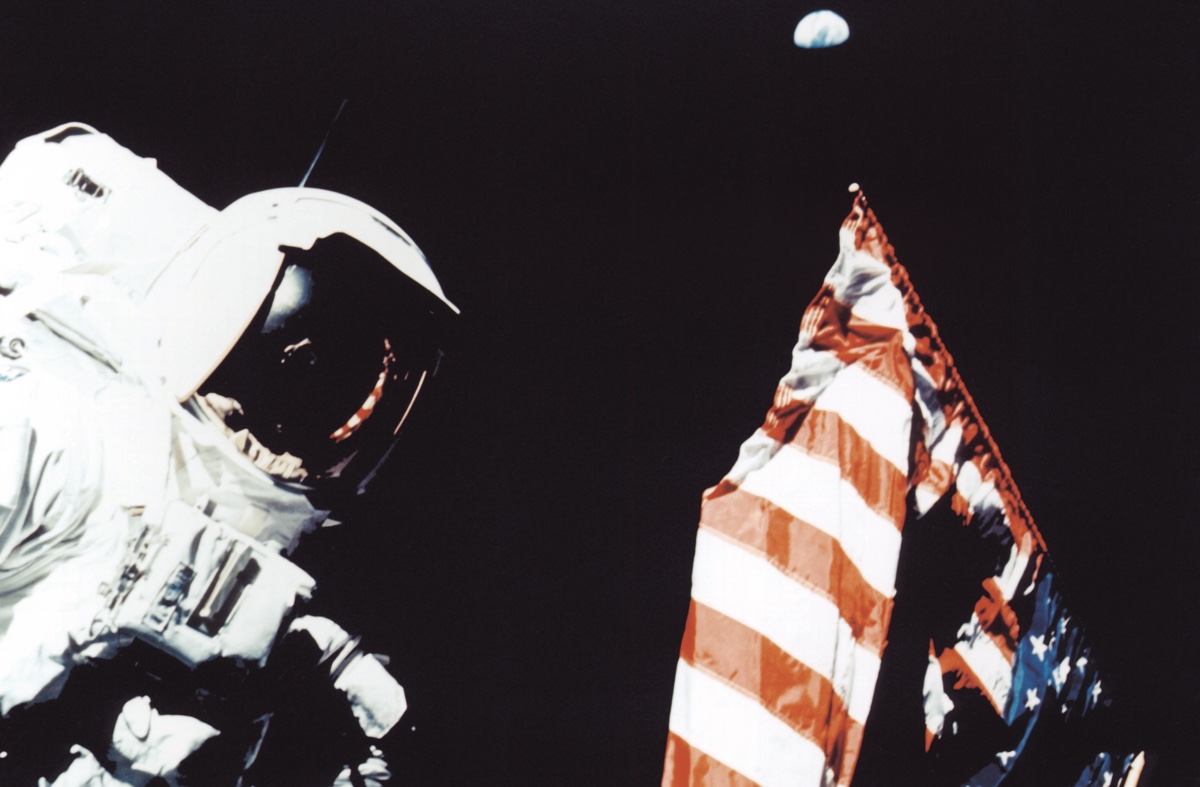 Astronaut Harrison Schmitt with the American flag and the Earth in the background, during a trek on the lunar surface as part of the Apollo 17 mission.