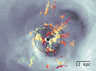 An image shows how galaxy-sized bubbles shove gas around in the Perseus galaxy cluster. The X at the center of the image shows the location of the supermassive black hole at its center.