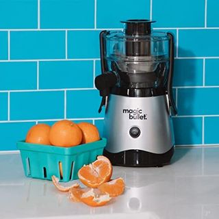 Magic Bullet mini juicer with fresh oranges on blue tiled background