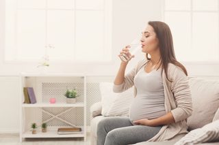 A pregnant woman drinking water.
