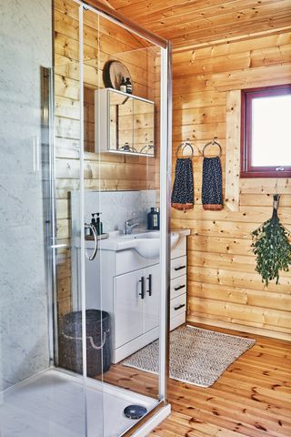 A panelled bathroom with white storage unit and shower enclosure