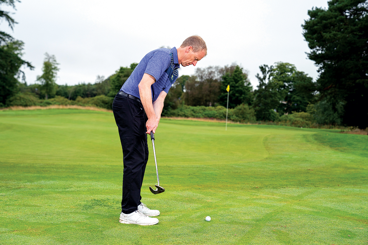 Neil Marr demonstrating a putt from the fringe of the green, with the flag on another tier up towards the back right portion of the green