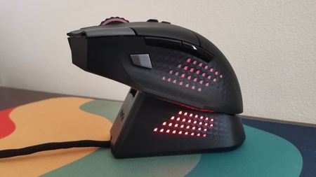 An MSI Versa Pro mouse on a desk with a charging dock and accessories.