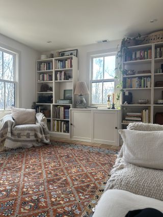 A living room with built-in bookshelves and a red patterned rug