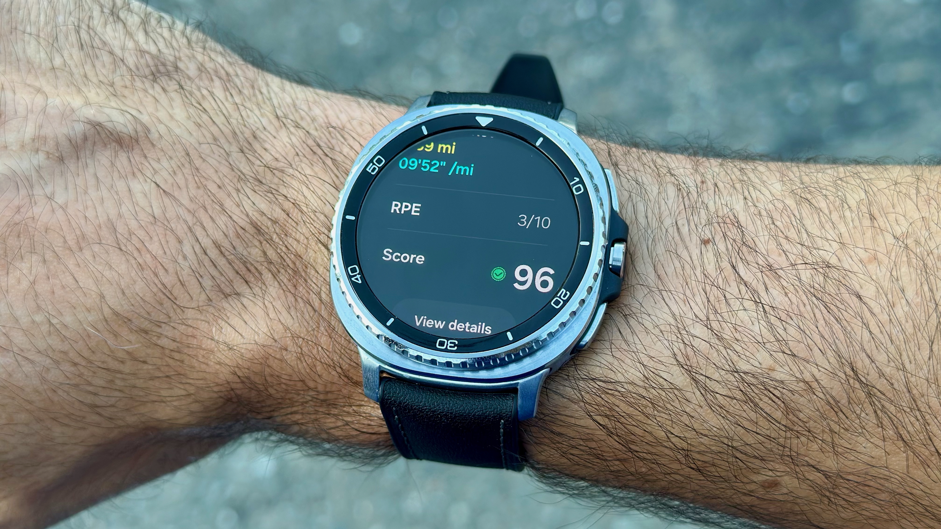 The Samsung Galaxy Watch 8 Classic on a wrist showing a post-run pace, estimated difficulty level, and Running Coach score.