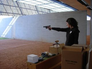 Emily Jacir inside a gun rage pointing a gun