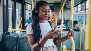 How to gift music streaming services: Woman listening to music through headphones on a bus