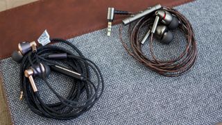 1MORE Triple Driver Headphones coiled up on cloth surface