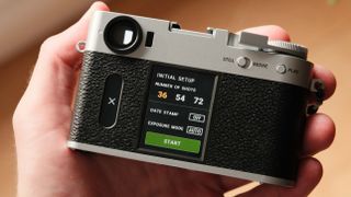 Fujifilm X Half camera held in a hand showing the film camera mode