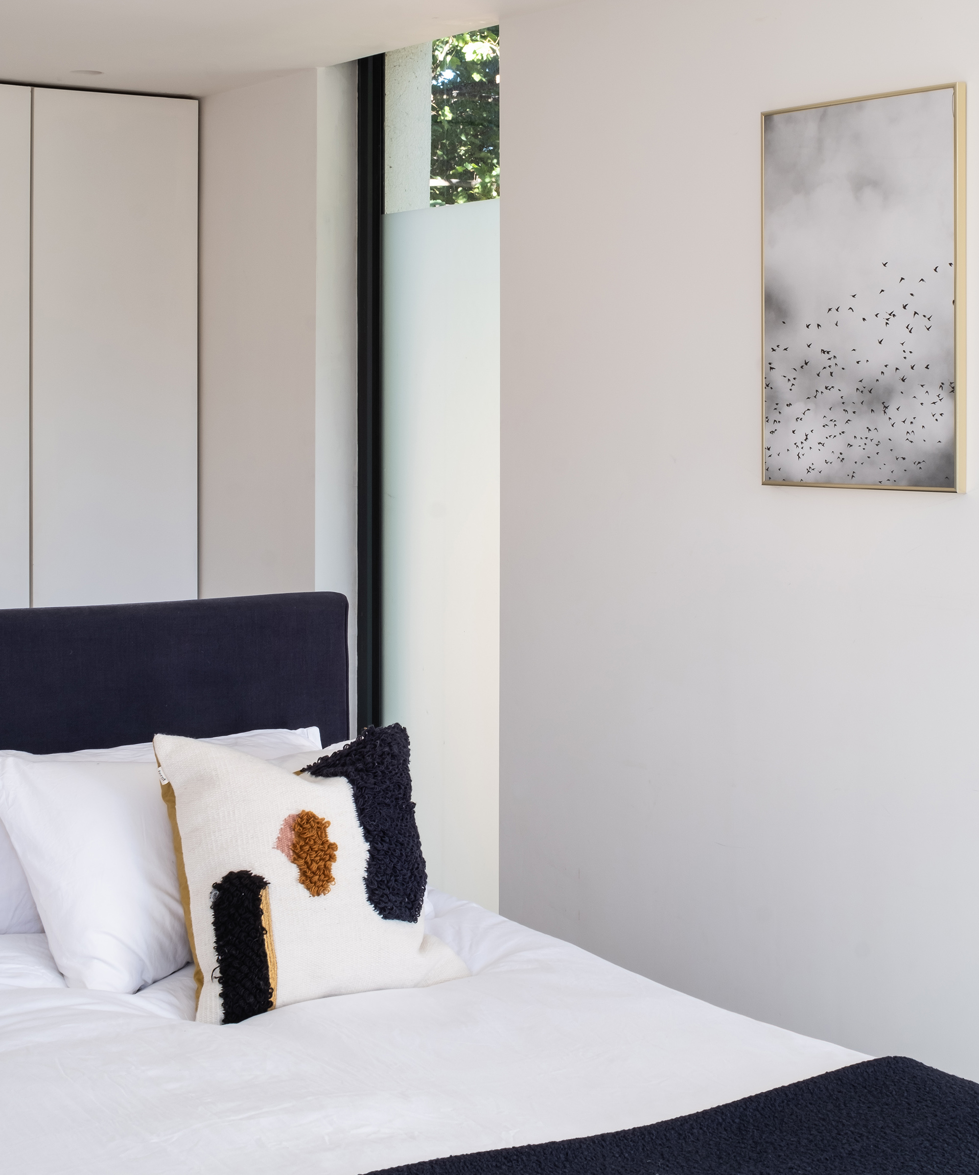 View of a bed in a white bedroom with netural wall art