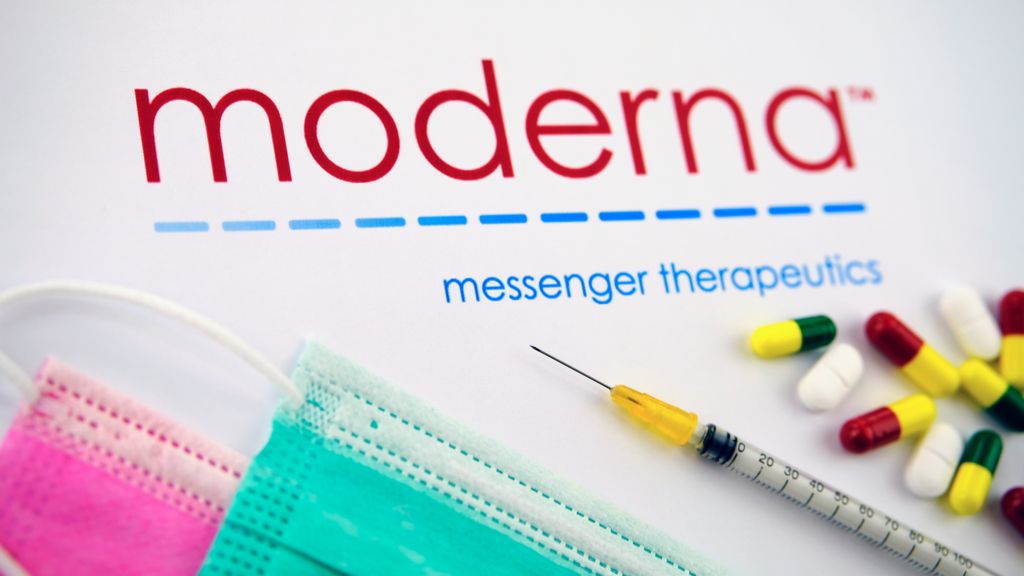 moderna logo above face masks, syrigne, pills on a table