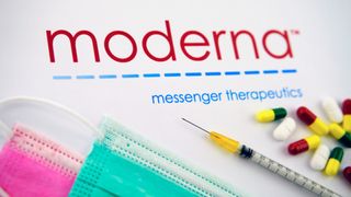 moderna logo above face masks, syrigne, pills on a table