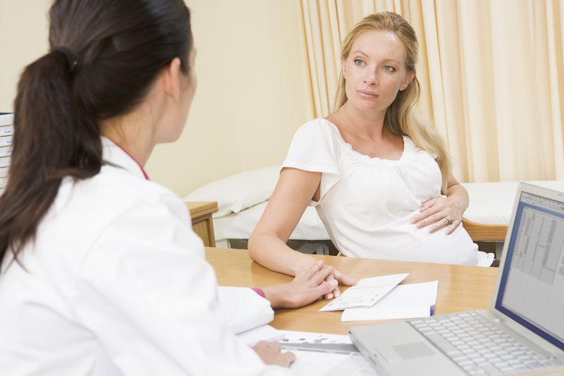 A pregnant woman talks with her doctor.