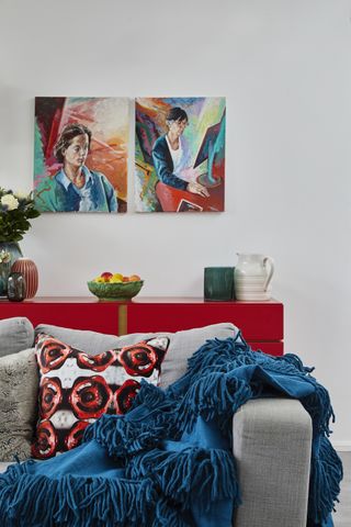 Living room with gray couch with blue throw and red patterned pillow and red cabinet