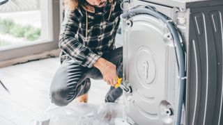 Man in a Kitchen Repairing a Washing Machine