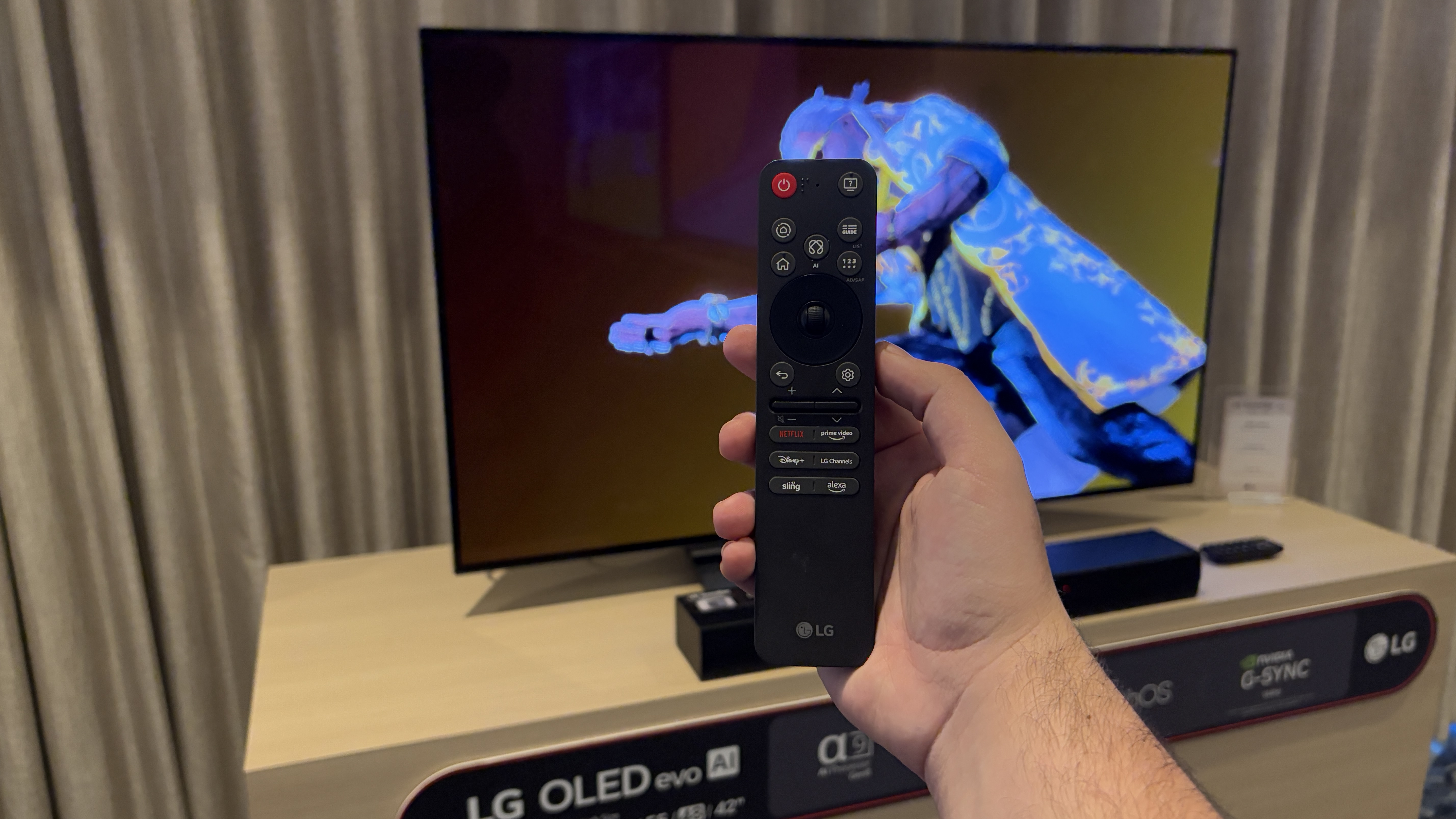 LG C5 remote in hand with the TV in the background