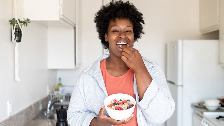 Woman eating from a bowl of fruit and granola