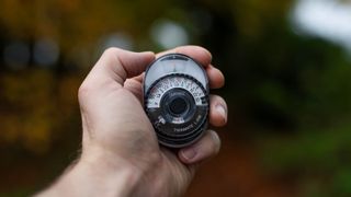 Sekonic Twinmate L-208 held in palm of hand against autumnal backdrop