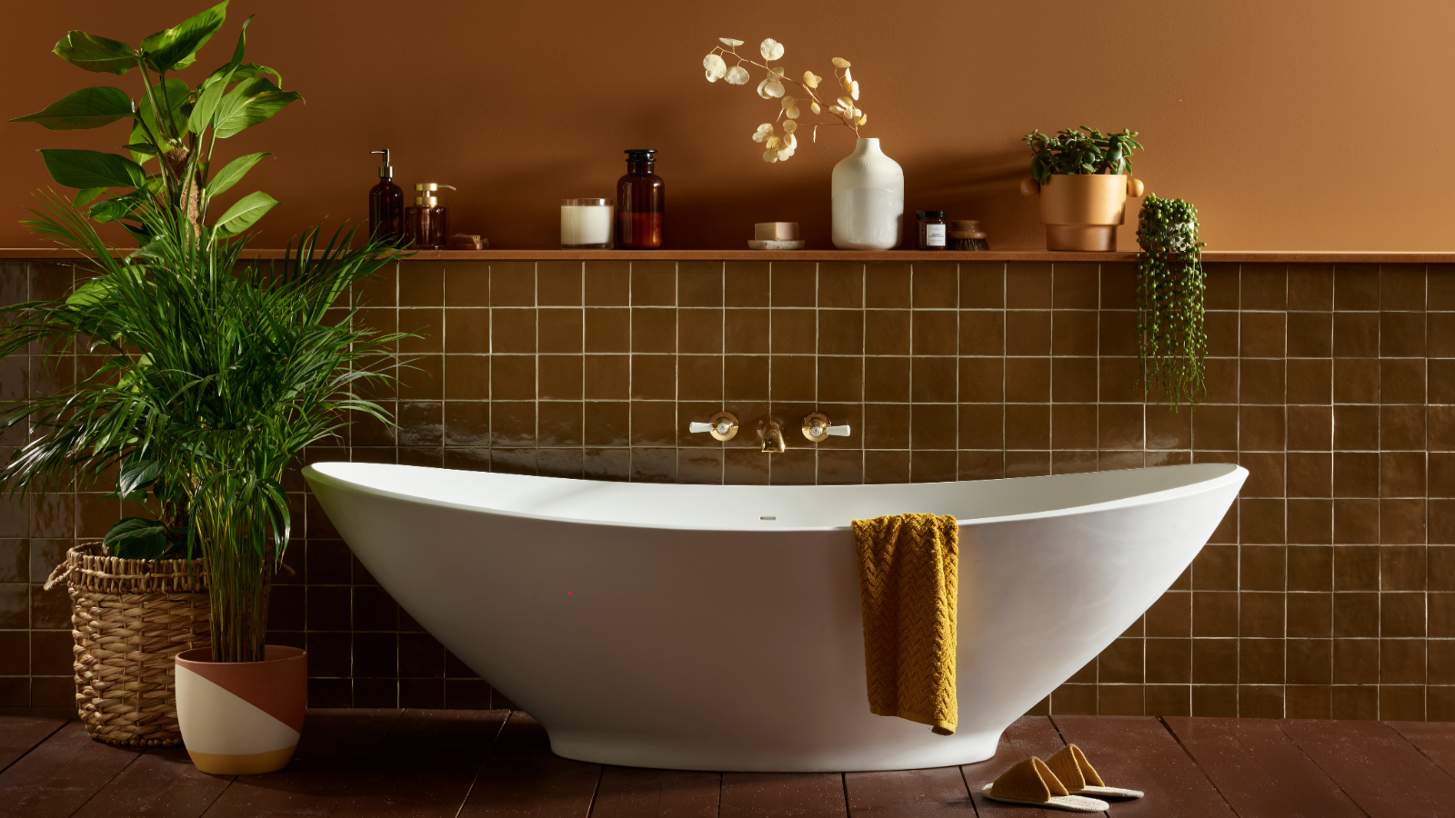 Bathroom with brown wall that's half tiled and half painted behind a freestanding bath