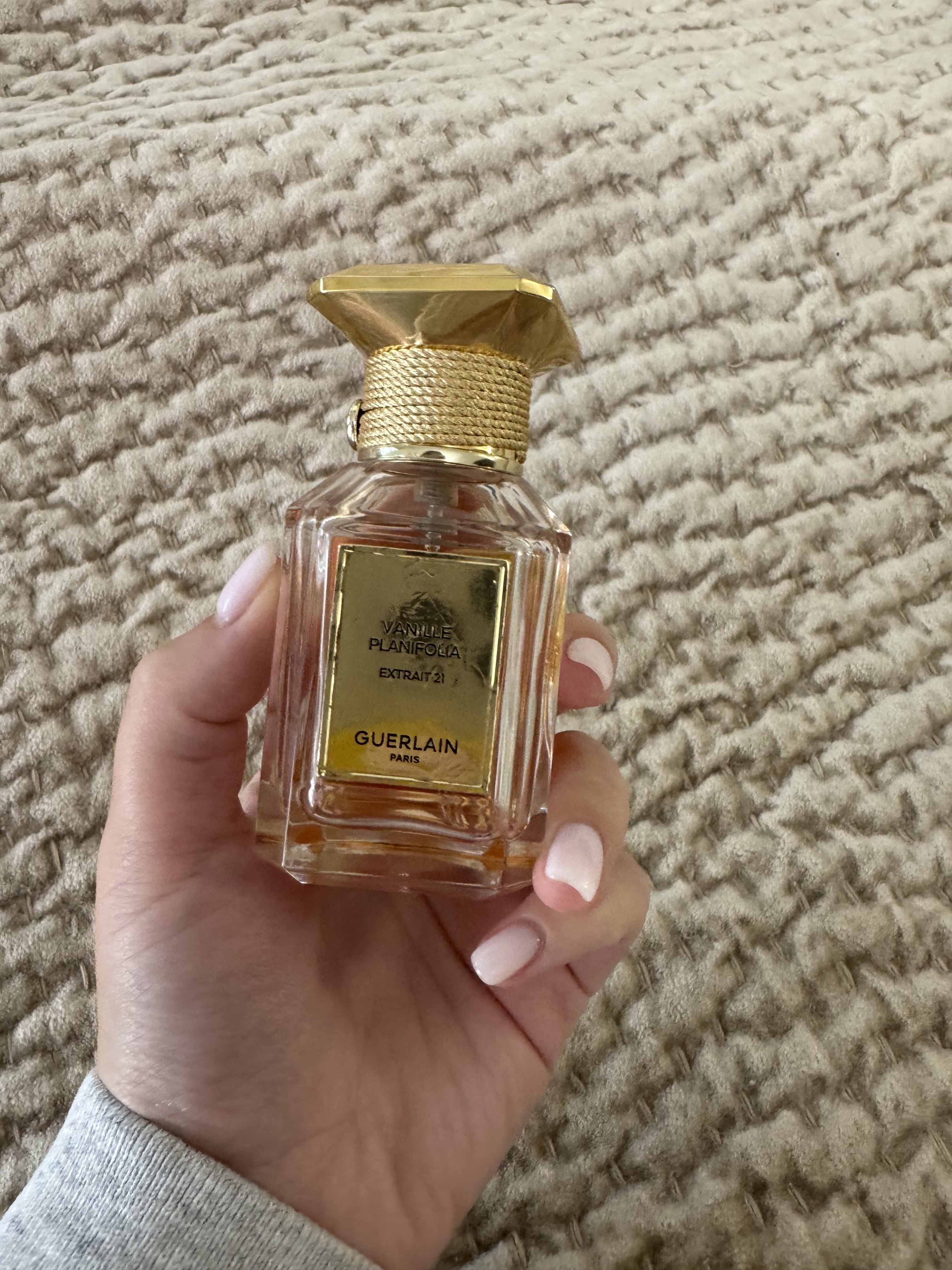 hand with pink nails holding guerlain perfume bottle