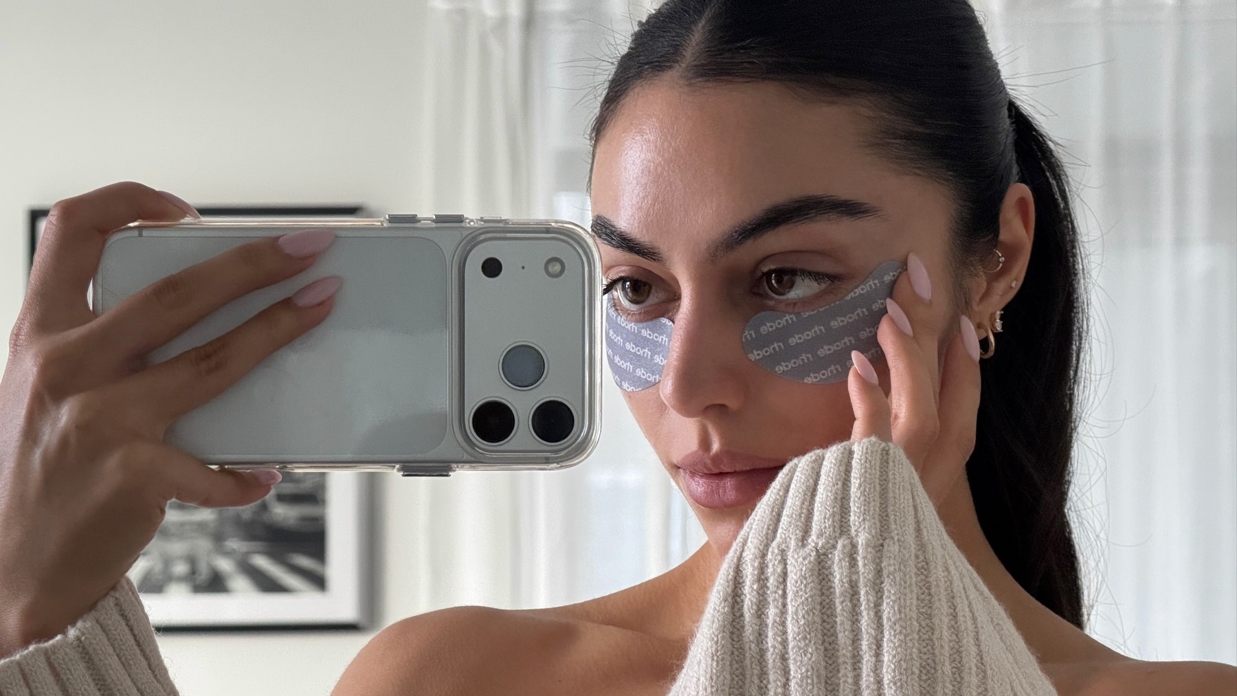 Photo of a woman wearing eye patches taking a mirror selfie