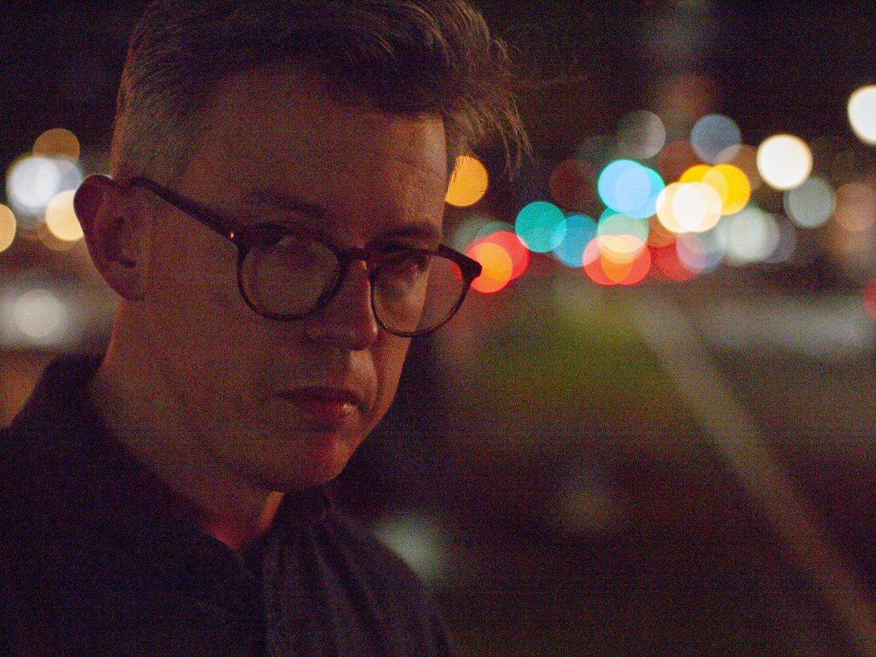 Portrait of a man at night in a city, there are blurred circular light behind him, shot with the Panasonic Lumix G1