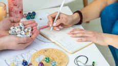 person writing in a notebook, with crystal and stones surround them on a desk