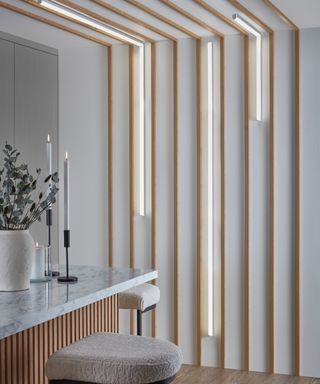 individual wooden slats run up wall and across ceiling with thin LED strip lights also run in three different places