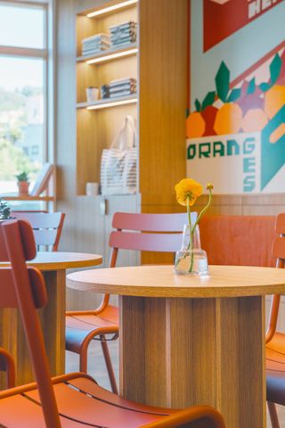 The colorful, school market-inspired interiors of a cafe mix industrial details such as iron chairs and wooden tables with colorful murals.