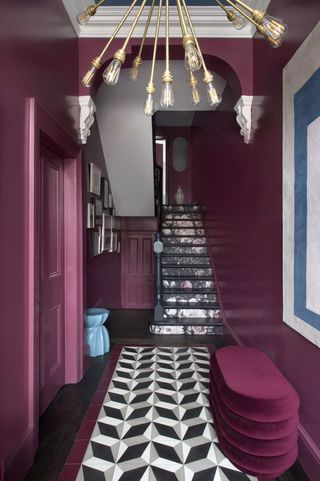 Plum hallway with black and white tiles and wallpaper stairs