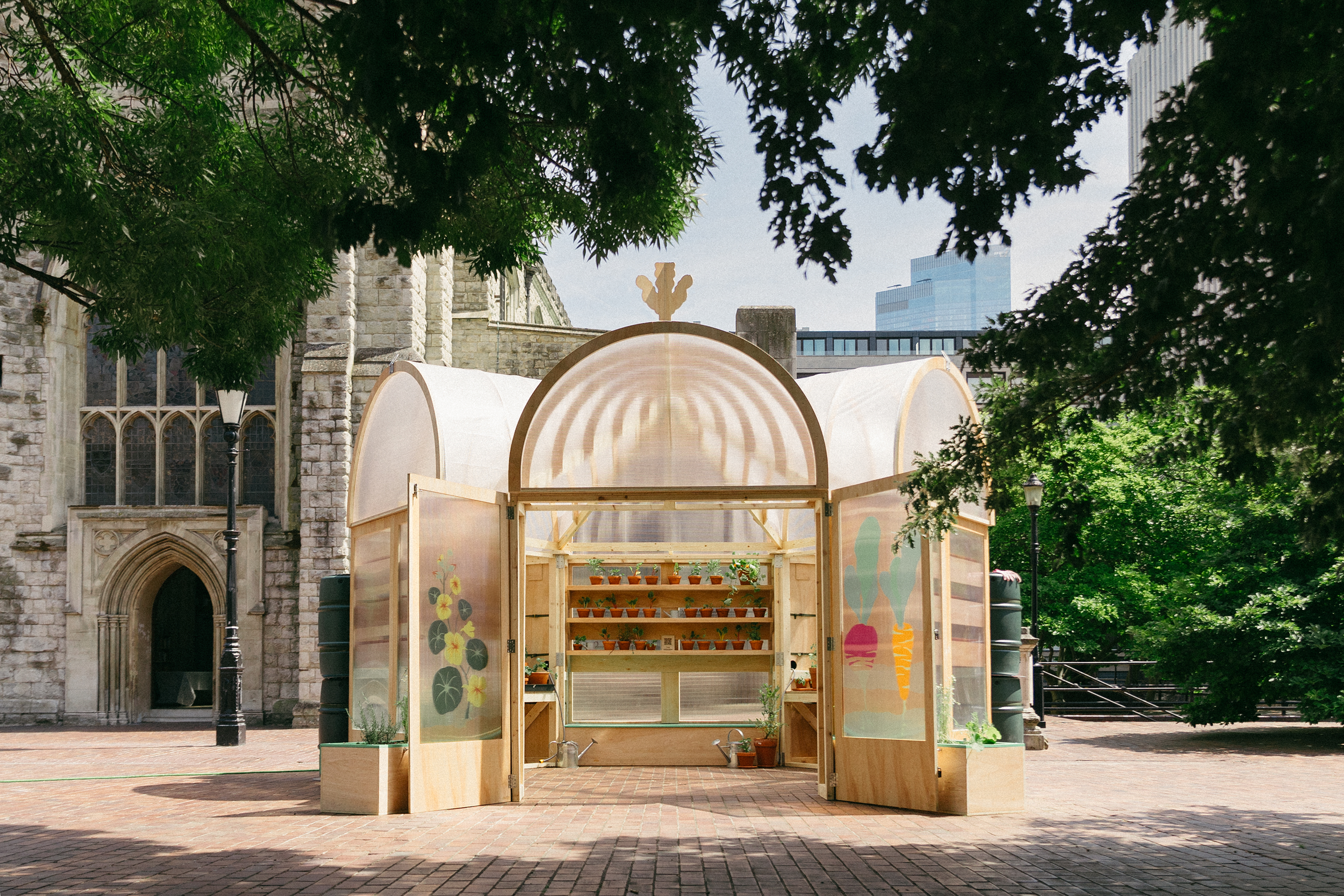 The Veggery, a greenhouse pavilion installed outside in a London plaza, made of wood and featuring a variety of plant pots on shelves