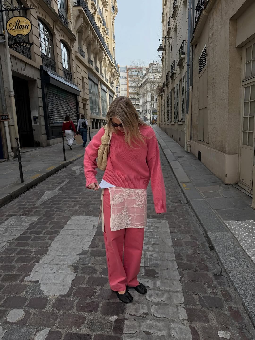 A woman wearing a coral pink pant set and an ivory crochet skirt, one of the biggest 2026 spring color pairings.