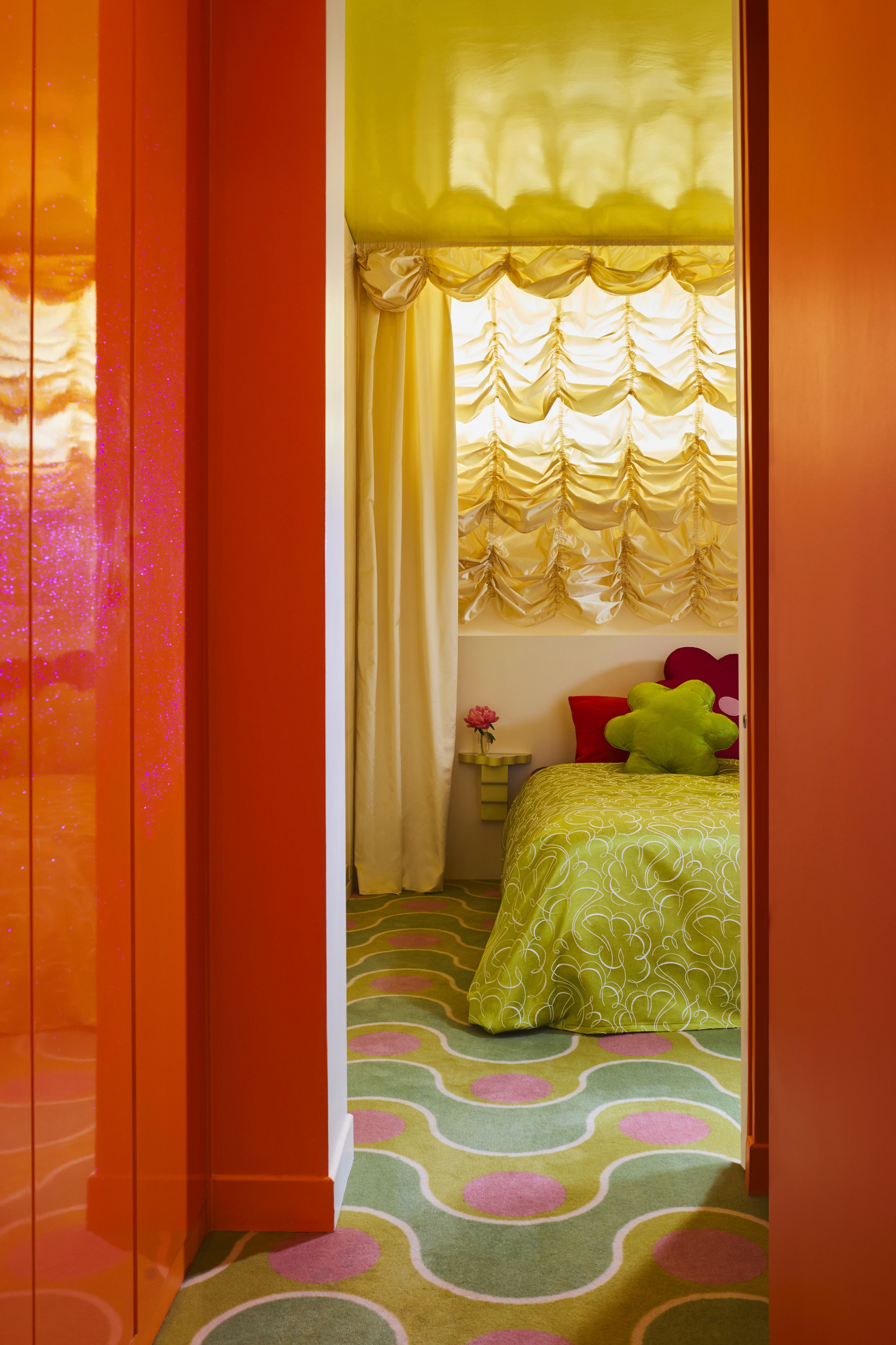 a retro bedroom with yellow curtains styled like a theatre, with patterned colorful flooring