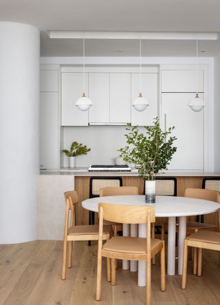 A minimal dining room with bright white walls and wooden furniture