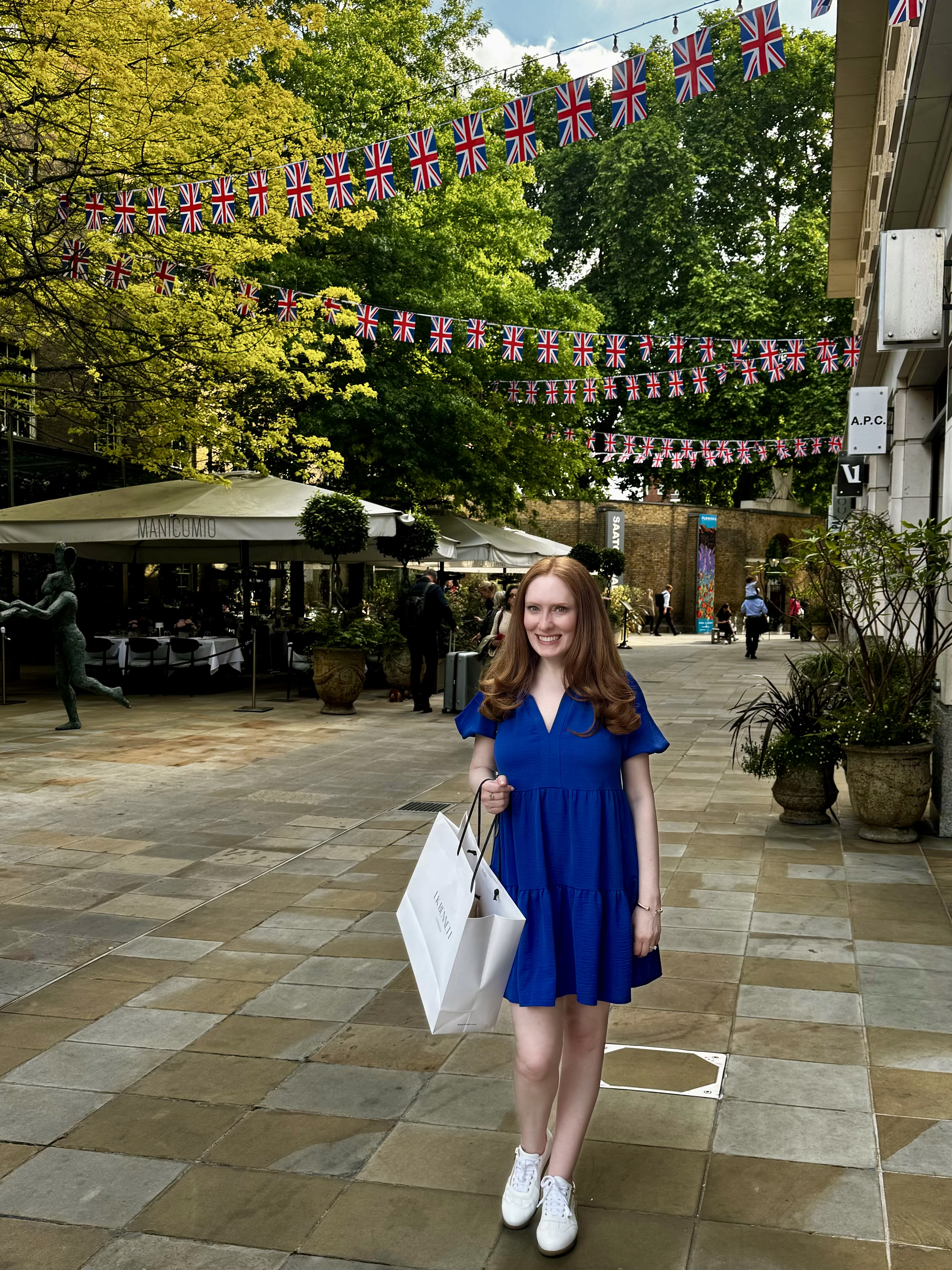 Kristin Contino wearing a blue dress standing in front of Union Jack bunting
