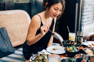 Woman eating food at a restaurant during while doing the Banting diet