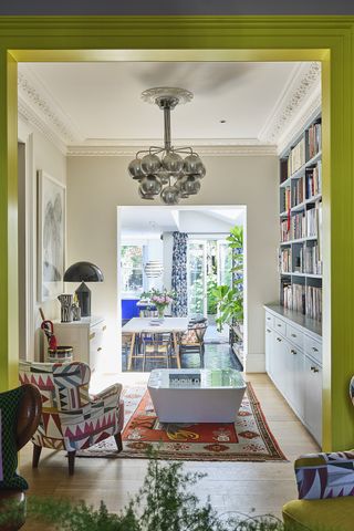 Bright narrow living room in a townhouse with shelves and a glossy green painted arch