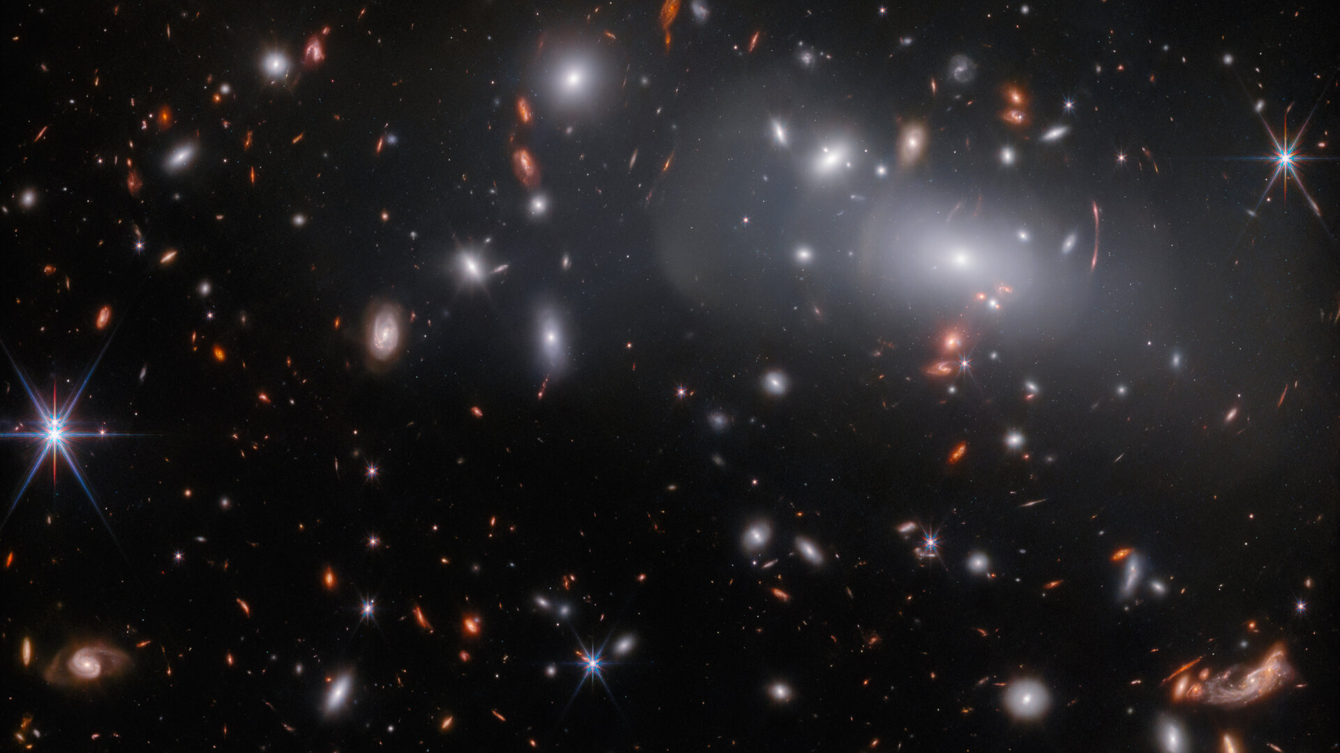 una gran galaxia elíptica rodeada por muchas galaxias más pequeñas similares, como se ve desde el Telescopio Espacial James Webb.