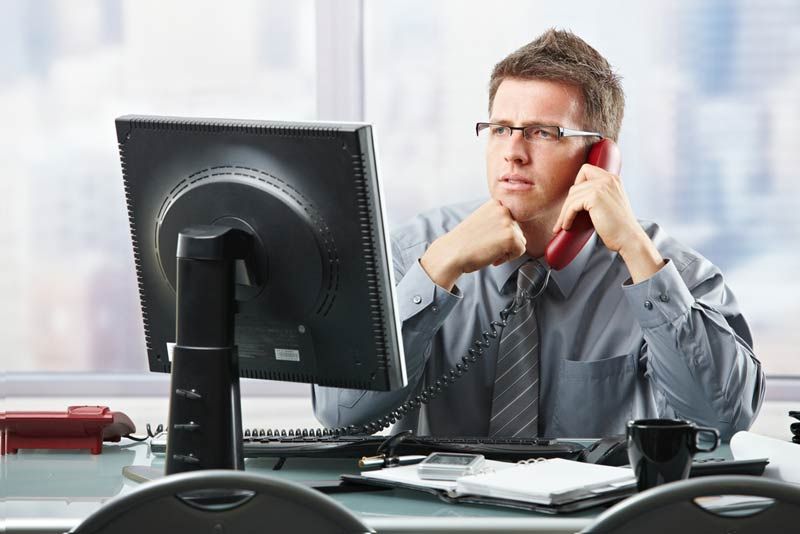 man sitting at desk and talking on the phone.