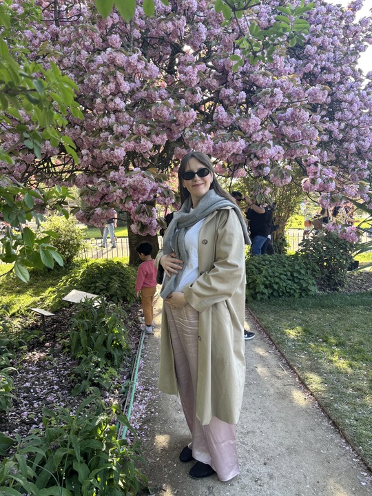 Halie LeSavage in Paris wearing silk pants and a trench coat while seven months pregnant