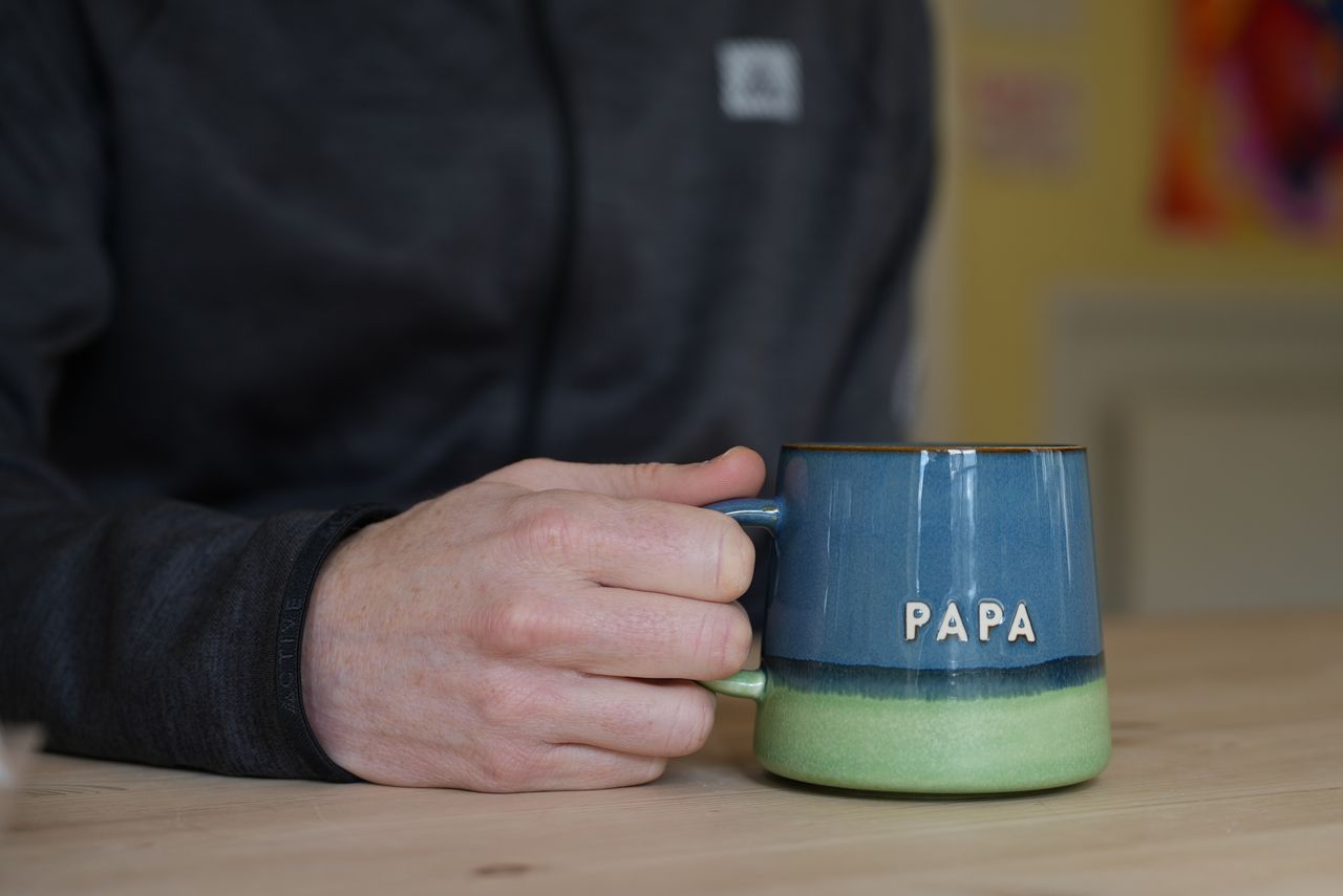 A hand holding a small mug