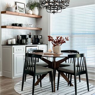 Round black dining table and chairs over striped contemporary rug in modern small kitchen with white cabinets